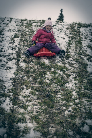 Germany, Bavaria, Landshut, laughing little girl tobogganing stock photo