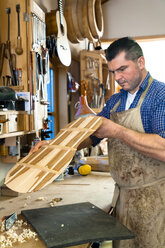 Gitarrenbauer in seiner Werkstatt - TC003845