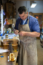 Gitarrenbauer in seiner Werkstatt - TC003897