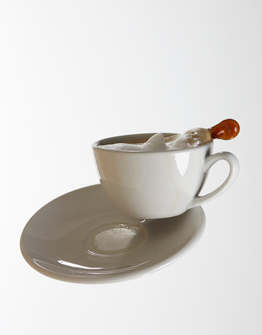 Weiße Kaffeetasse mit weißem Kaffee und Untertasse fallen vor weißem Hintergrund, lizenzfreies Stockfoto