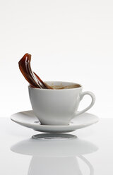 Schwarzer Kaffee spritzt aus einer weißen Kaffeetasse vor weißem Hintergrund - AKF000305