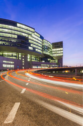 Germany, Baden-Wuerttemberg, Stuttgart, office building and light trails on street at twilight - WDF002244