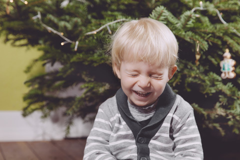 Laughing toddler under Christmas tree at home stock photo