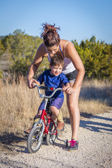USA, Texas, Mutter hilft Sohn beim Fahrradfahren - ABAF001210