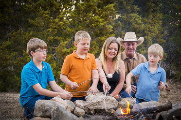 USA, Texas, Family Roasting marshmallows over camp fire - ABAF001197