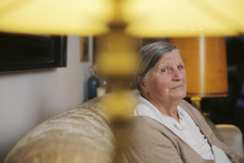 Senior woman sitting on a couch at living room - JATF000662