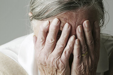 Ältere Frau bedeckt ihr Gesicht mit den Händen - JATF000635