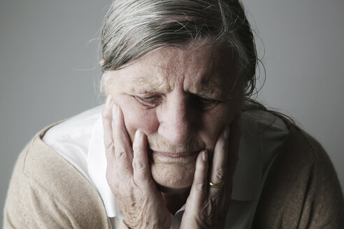 Portrait of senior woman with closed eyes and head in her hands - JATF000639