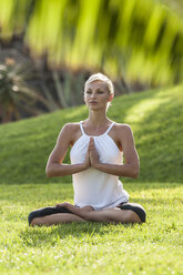 Frau übt Yoga auf einer Wiese - EGF000114