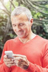 Älterer Mann schaut auf sein Smartphone - MFF000849