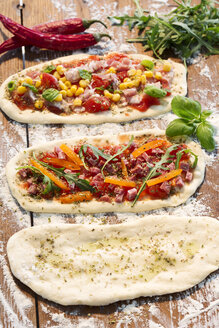 Roher Pizzateig, mit Schinken, Käse, Tomaten, Rucola, Mais, Paprika, Knoblauchöl und Basilikum - MAEF007696