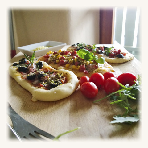 Pizzabrötchen, belegt mit Tomate, Mozzarella, Rucola, Mais, Salami, Schinken, Oliven, Studio, lizenzfreies Stockfoto