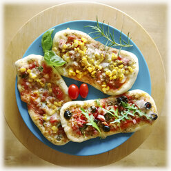Pizzabrötchen, belegt mit Tomate, Mozzarella, Rucola, Mais, Salami, Schinken, Oliven, Studio - MAEF007714