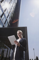 Businesswoman outside office building using tablet pc - CHAF000086