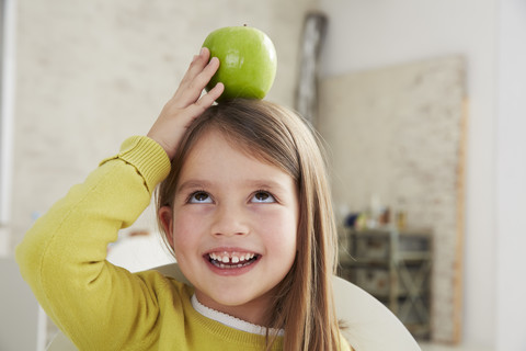 Deutschland, München, Mädchen sitzt am Tisch mit grünem Apfel, lizenzfreies Stockfoto