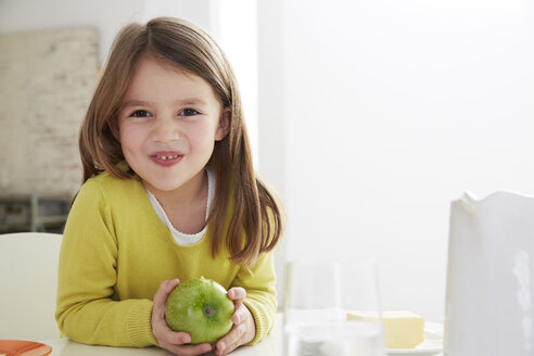 Germany, Munich, Girl sitting at table with green apple - FSF000177