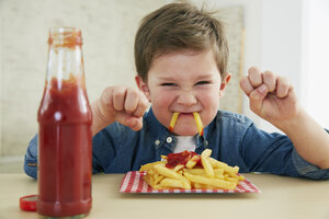 Deutschland, München, Junge isst Pommes frites mit Ketchup - FSF000196