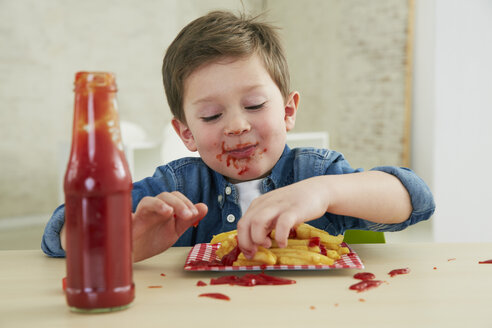 Deutschland, München, Junge isst Pommes frites mit Ketchup - FSF000199