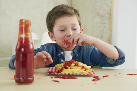 Deutschland, München, Junge isst Pommes frites mit Ketchup, lizenzfreies Stockfoto
