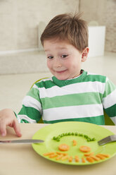 Germany, Munich , Boy eating peas and carrots showing anthropomorphic face - FSF000185