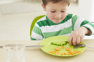 Germany, Munich , Boy eating peas and carrots showing anthropomorphic face - FSF000148