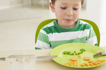 Germany, Munich , Boy eating peas and carrots showing anthropomorphic face - FSF000147