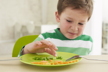 Germany, Munich , Boy eating peas and carrots showing anthropomorphic face - FSF000146