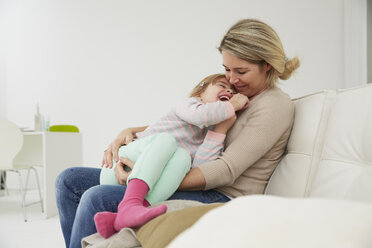 Germany, Munich, Mother and daughter sitting on sofa, cuddling - FSF000132