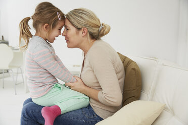 Deutschland, München, Mutter und Tochter auf dem Sofa sitzend, kuschelnd - FSF000131