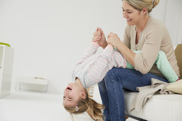 Germany, Munich, Mother and daughter sitting on sofa, goofing around - FSF000130