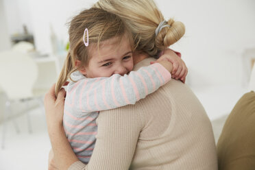 Germany, Munich, Mother and daughter sitting on sofa, cuddling - FSF000125