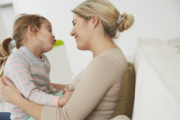 Deutschland, München, Mutter und Tochter auf dem Sofa sitzend, kuschelnd - FSF000123