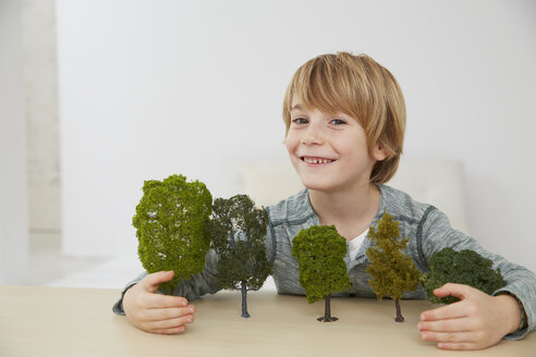 Deutschland, Junge sitzt am Tisch mit Baummodellen, Umweltschutz - FSF000107