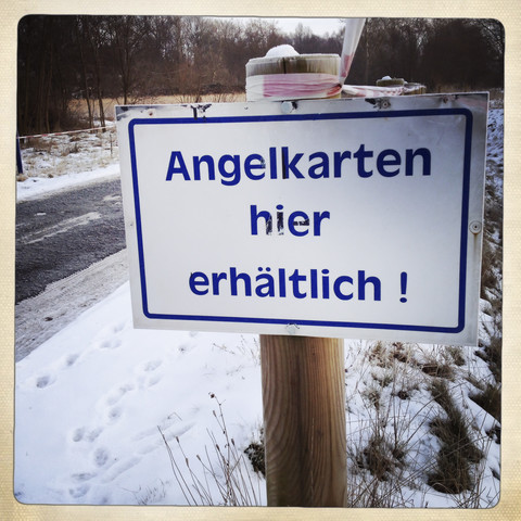 Schild für Angelkarten an verschneiter Straße, Brandenburg, Deutschland, lizenzfreies Stockfoto