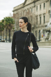 Spain, Catalunya, Barcelona, young black dressed businesswoman in front of a street - EBSF000001