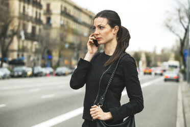 Spanien, Katalonien, Barcelona, junge schwarz gekleidete Geschäftsfrau beim Telefonieren vor einer Straße - EBSF000008