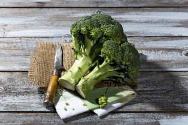 Brokkoli und Messer auf Jute- und Stoffserviette auf Holztisch - MAEF007761