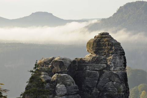 Deutschland, Sachsen, Nationalpark Sächsische Schweiz, Elbsandsteingebirge, Blick auf Felsformation mit Morgennebel im Hintergrund, lizenzfreies Stockfoto