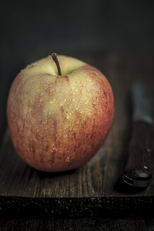 Apfel mit Wassertropfen und Messer auf Schneidebrett - SBDF000568