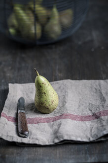 Birne mit Wassertropfen und Messer auf Küchenhandtuch, Korb mit Birnen - SBDF000569