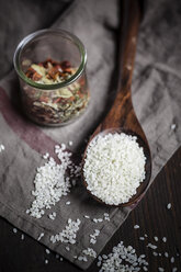 Risotto rice on wooden spoon and mixed spices in a glass - SBDF000585