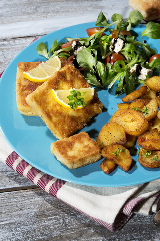 Gebackener Bio-Tofu mit Bratkartoffeln und Feldsalat mit Tomaten und Balsamico, lizenzfreies Stockfoto