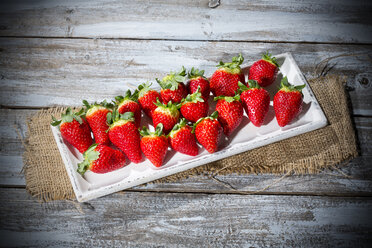 Teller mit Erdbeeren (Fragaria) auf einem Tisch aus Jute und Holz - MAEF007837