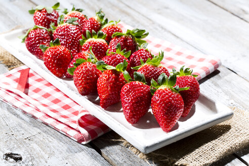 Teller mit Erdbeeren (Fragaria) auf Jute, Küchenhandtuch und Holztisch - MAEF007842