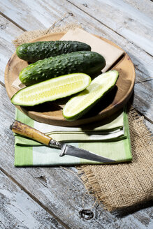 Geschnittene und ganze Gurken (Cucumis sativus) mit dem Messer auf dem Schneidebrett - MAEF007823