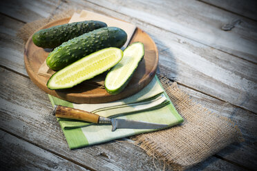 Geschnittene und ganze Gurken (Cucumis sativus) mit dem Messer auf dem Schneidebrett - MAEF007824