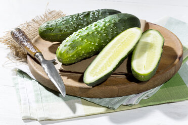 Geschnittene und ganze Gurken (Cucumis sativus) mit dem Messer auf dem Schneidebrett - MAEF007827