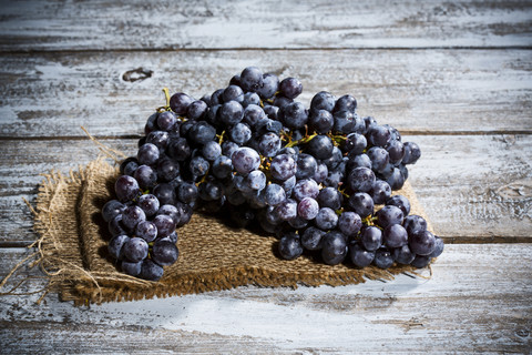 Kernlose blaue Weintrauben auf Jute und Holztisch, lizenzfreies Stockfoto