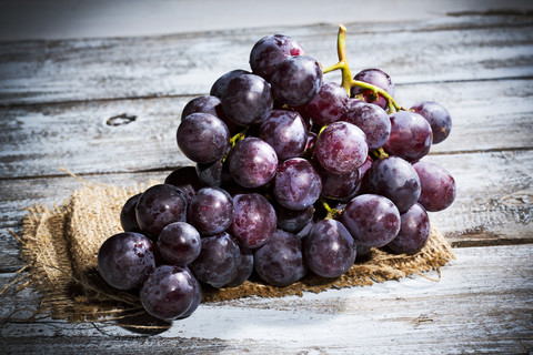 Red grapes on jute and wooden table stock photo