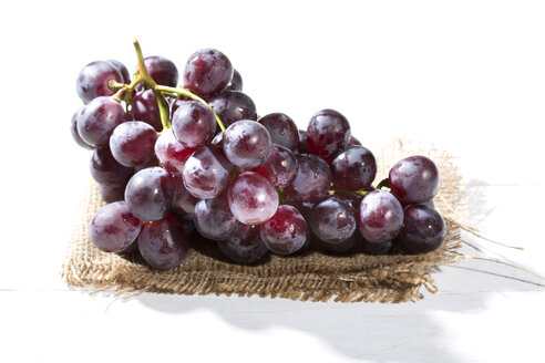 Rote Weintrauben auf Jute und weißem Holztisch - MAEF007866